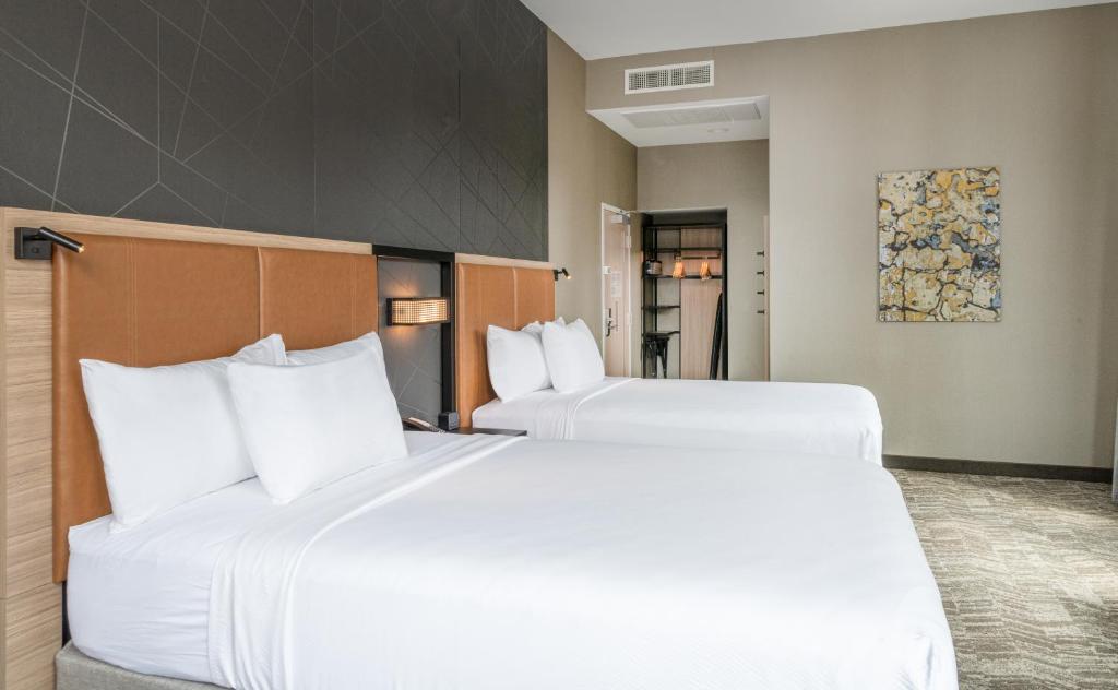 Dos camas en una habitación de hotel con almohadas blancas. en SpringHill Suites by Marriott Baltimore Downtown Convention Center Area, en Baltimore