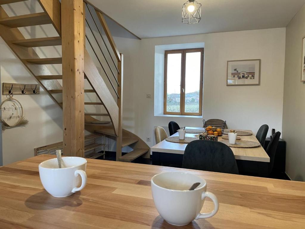 una sala da pranzo con un tavolo con due tazze sopra di Ancienne bergerie rénovée avec piscine et grand jardin en Auvergne - FR-1-489-411 a Durdat-Larequille