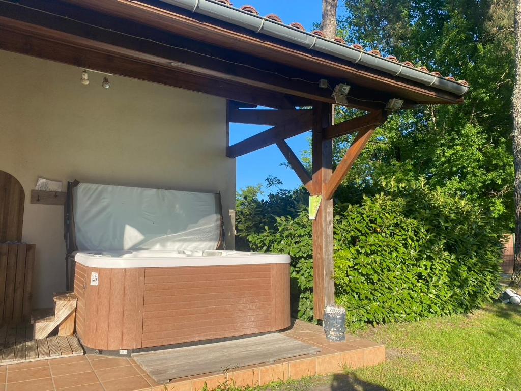 a hot tub sitting under a wooden pergola at Chambres d'Elisa in Saint-Morillon