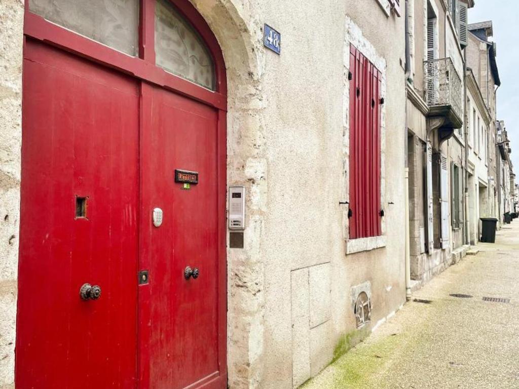 une porte rouge sur le côté du bâtiment dans l'établissement Triplex rénové 4 chambres au cœur de Blois avec wifi - FR-1-491-455, à Blois