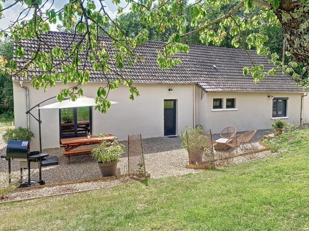 une petite maison blanche avec une table de pique-nique et un parasol dans l'établissement Gîte cosy en forêt avec terrasse, proche étang et loisirs, 3 chambres, wifi, plancha et parking - FR-1-489-453, à Cérilly