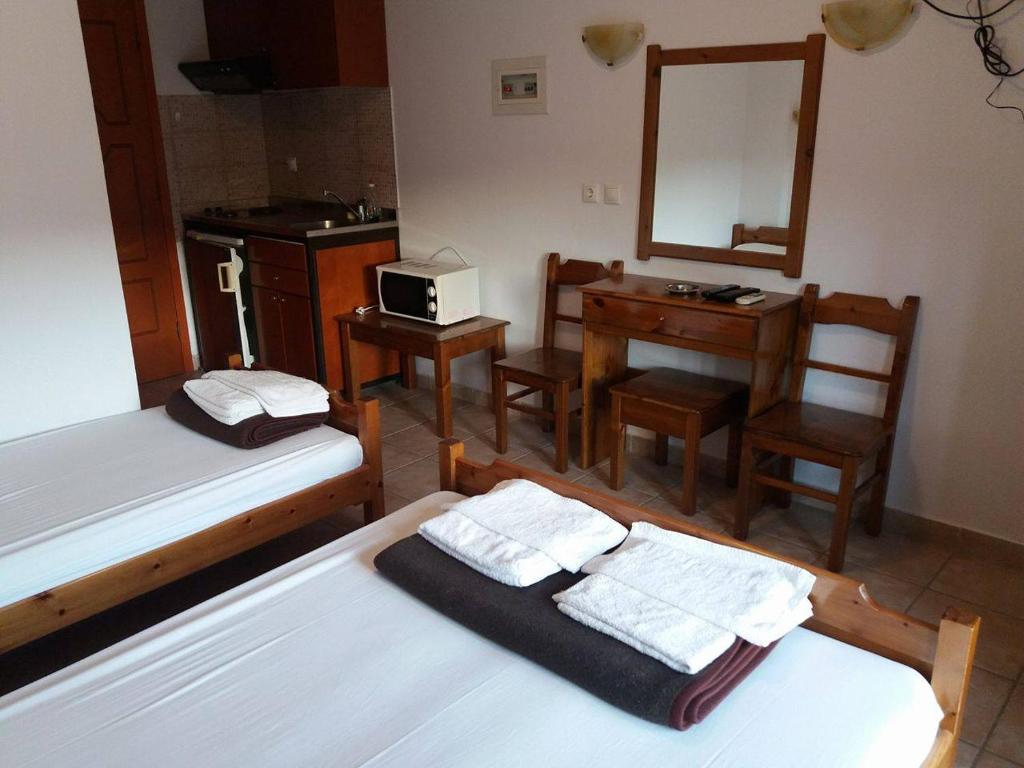 a bedroom with two beds and a desk and a mirror at Hotel Kosmas in Sarti