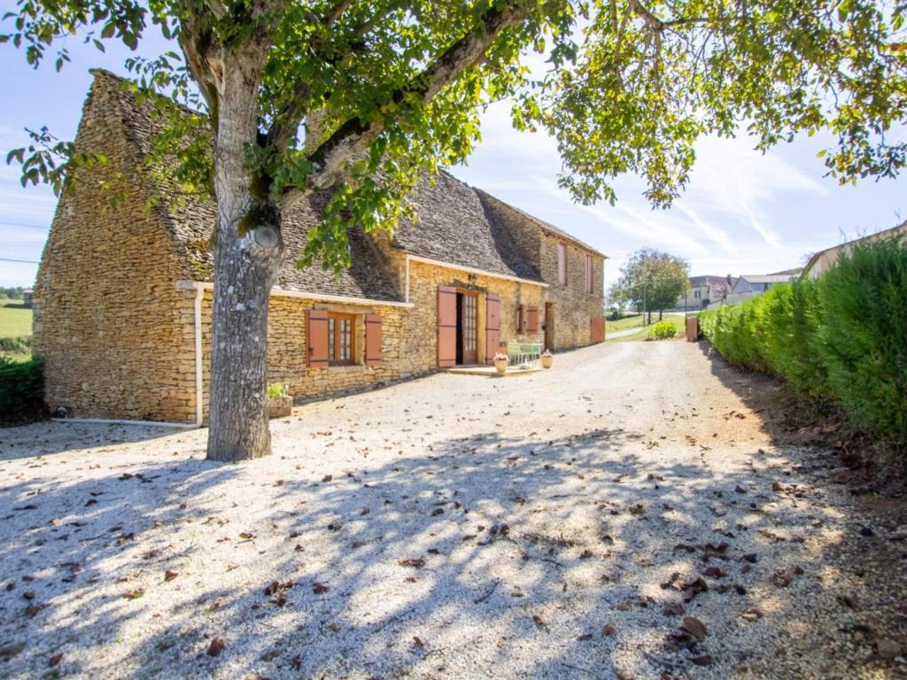 une vieille maison en pierre avec un arbre dans l'allée. dans l'établissement Maison rustique avec jardin et équipements pour enfants, proche Sarlat - FR-1-616-394, à Marcillac-Saint-Quentin