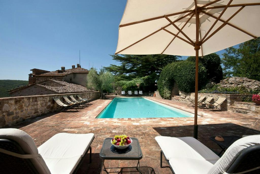 a pool with an umbrella and a table with a bowl of fruit at Traditional Apartment In The Heart Of Umbria in Poggio Aquilone