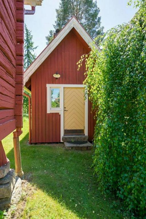 a red barn with a yellow door in a yard at Cozy Cottage By Töcksfors Lakes in Töcksfors