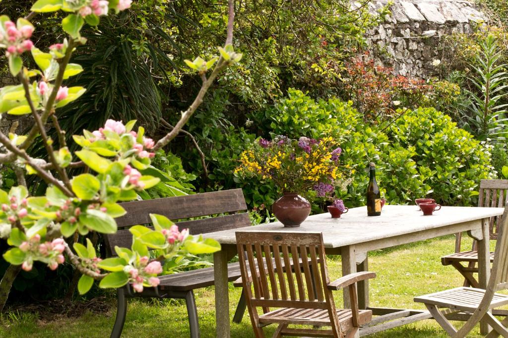 een tafel en stoelen in een tuin met bloemen bij Chambres de la Ville d'Ys in Cléden-Cap-Sizun