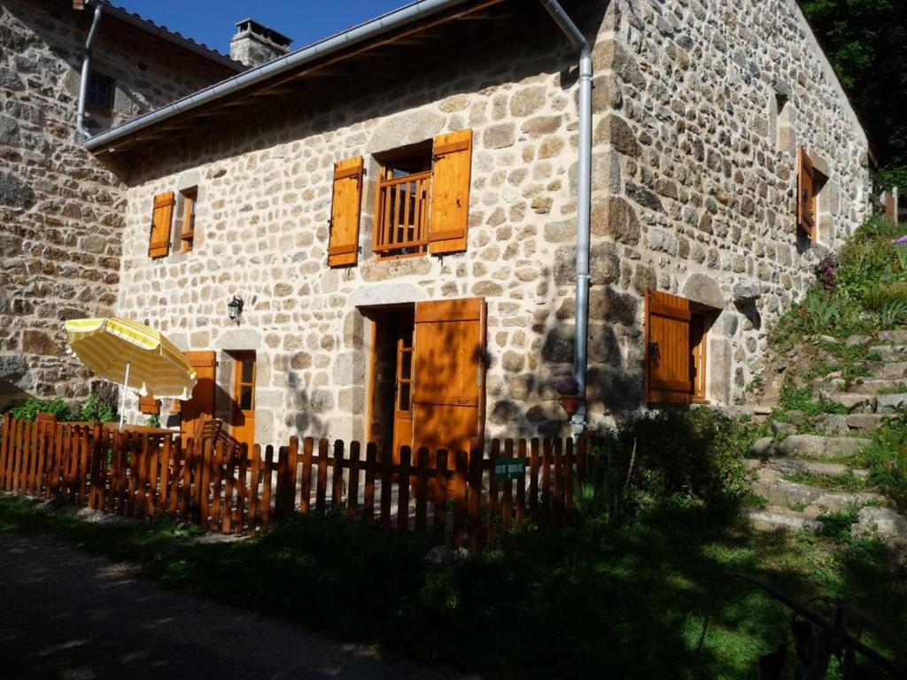 una vecchia casa in pietra con finestre in legno e recinzione di Charmant Gîte avec Terrasse, Cheminée et Jardin, à Proximité des Bois, Animaux Acceptés - FR-1-496-205 a Saint-Jean-Soleymieux