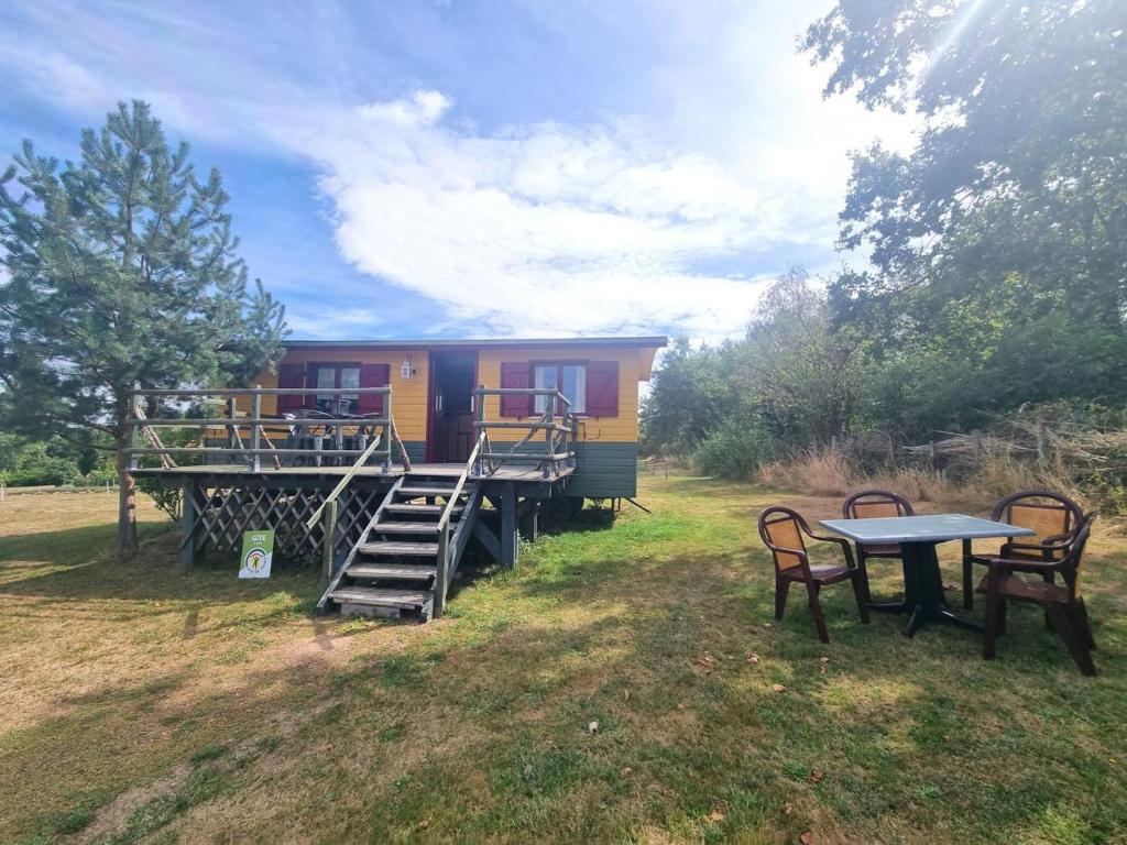 une maison avec une table et des chaises devant dans l'établissement Roulotte du Chat qui Pète: Séjour Paisible et Animaux Bienvenus - FR-1-496-308, à Saint-Germain-Lespinasse
