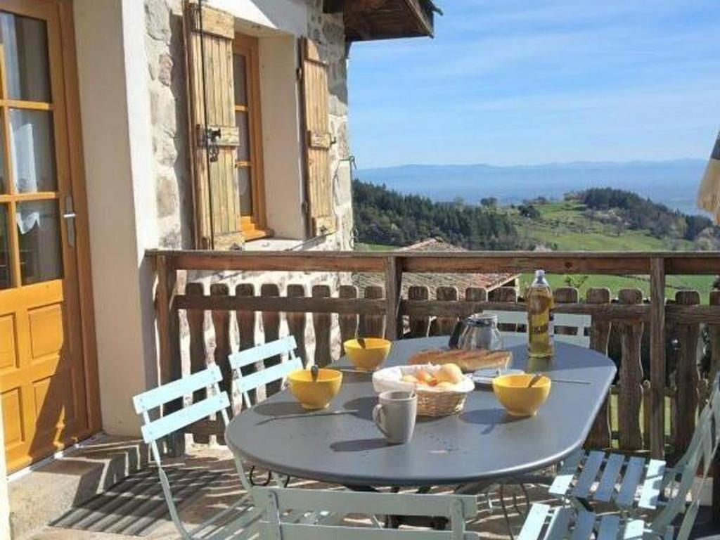 un tavolo con una ciotola di cibo su un balcone di Gîte rénové avec cheminée et jardin à 15 km des pistes de ski - FR-1-496-9 a Saint-Bonnet-le-Courreau