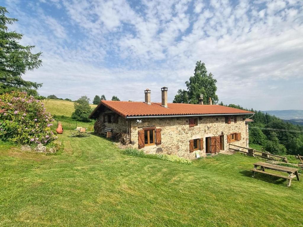 una casa de piedra en una colina con un banco en Gîte familial dans le massif du Pilat avec confort inclus - FR-1-496-294, en Doizieux