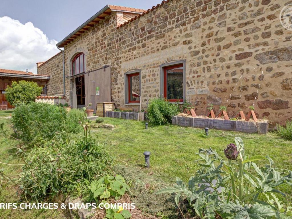 una vista esterna di un edificio in pietra con giardino di Gîte de charme avec terrasses et plancha - FR-1-496-327 a Verrières-en-Forez