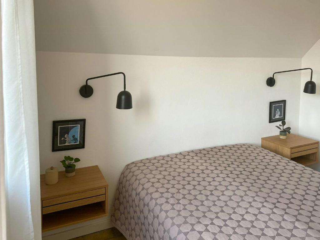 a bedroom with a bed and two tables and two lights at Modernized A-Frame House Near Saksild Beach in Odder