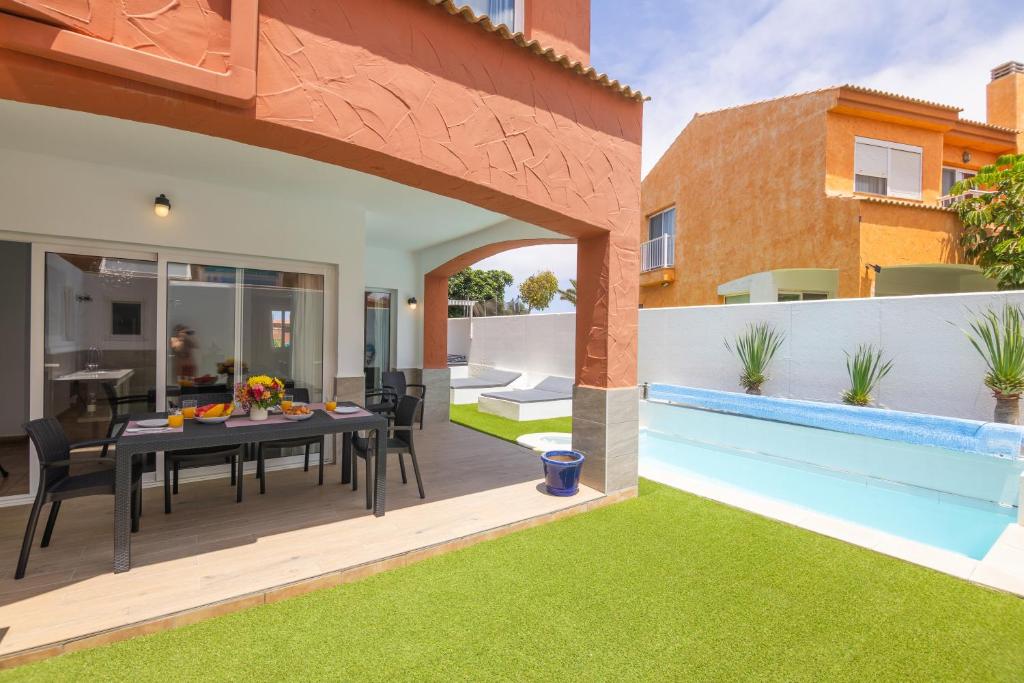 a patio with a dining table and a swimming pool at Casa Esther Corralejo in Corralejo