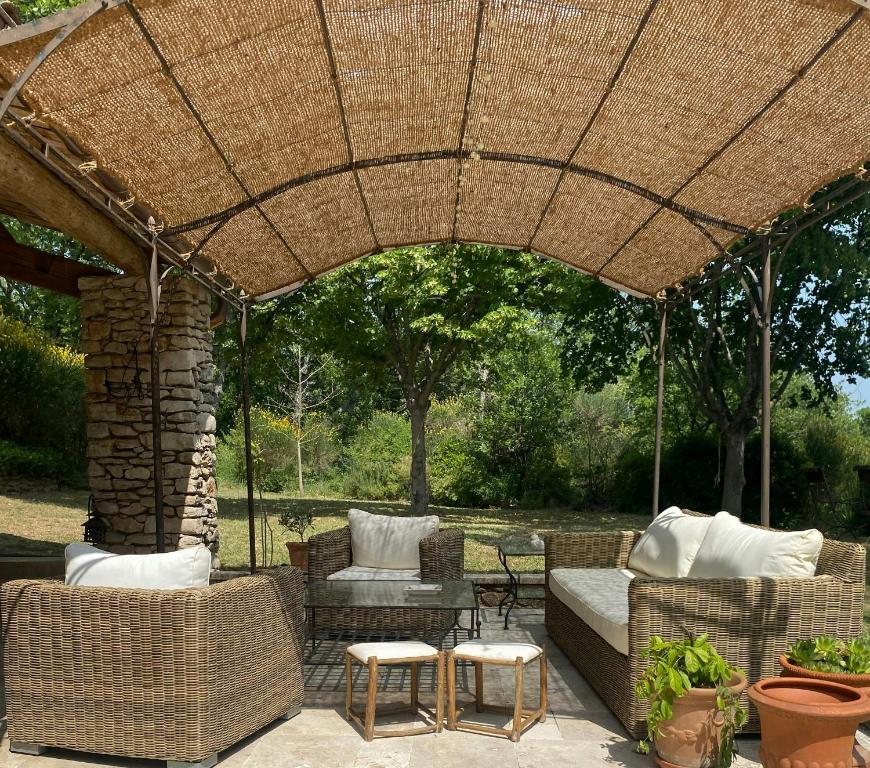 an outdoor patio with a wicker umbrella and chairs at Provencal Villa With Panoramic Views In Luberon in Apt