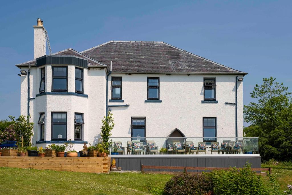 a large white house with tables and chairs at Toravaig House Hotel in Teangue