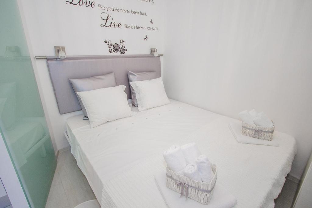 um pequeno quarto com uma cama com almofadas brancas e toalhas em Luxury Studio Apartment White Sensation em Vodice