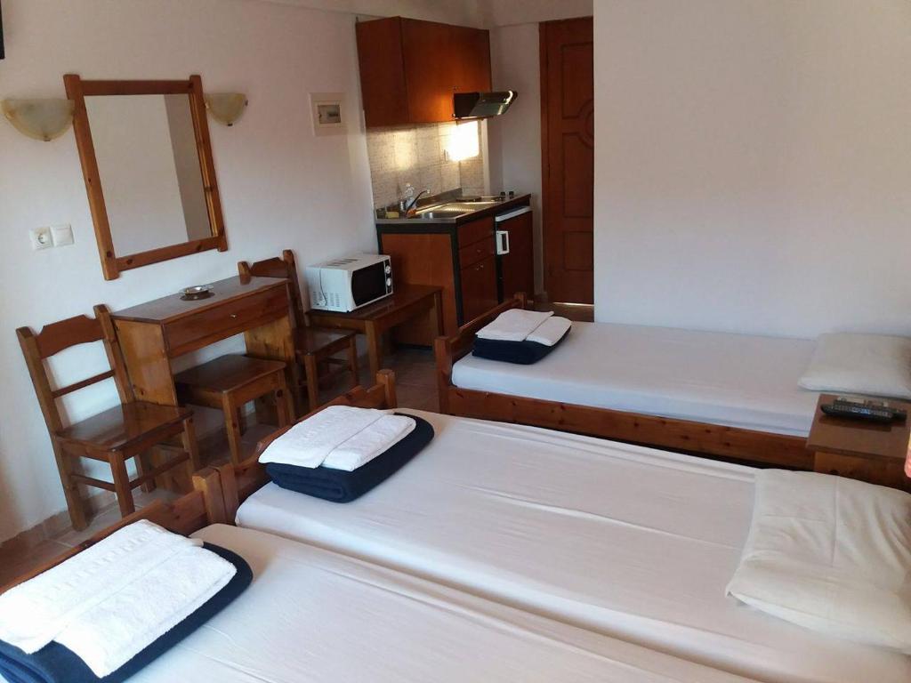a room with two beds and a desk and a mirror at Hotel Kosmas in Sarti