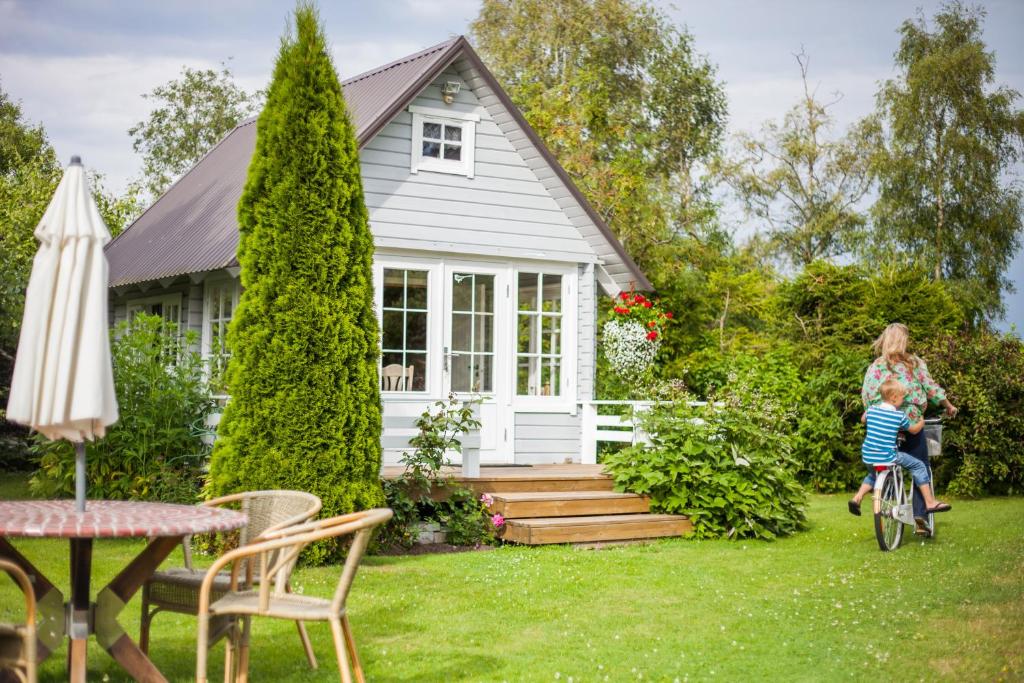 a woman and a child riding a bike in front of a house at Västriku Holiday Home in Nasva