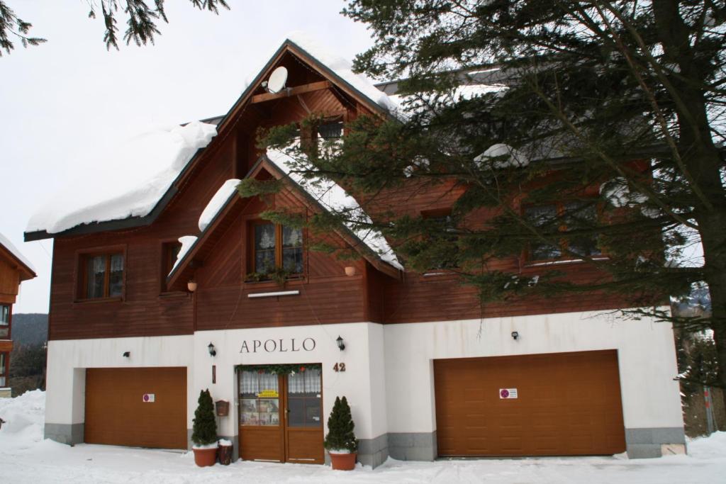 una casa con dos puertas de garaje en la nieve en Pension-Apartmany Apollo, en Špindlerův Mlýn