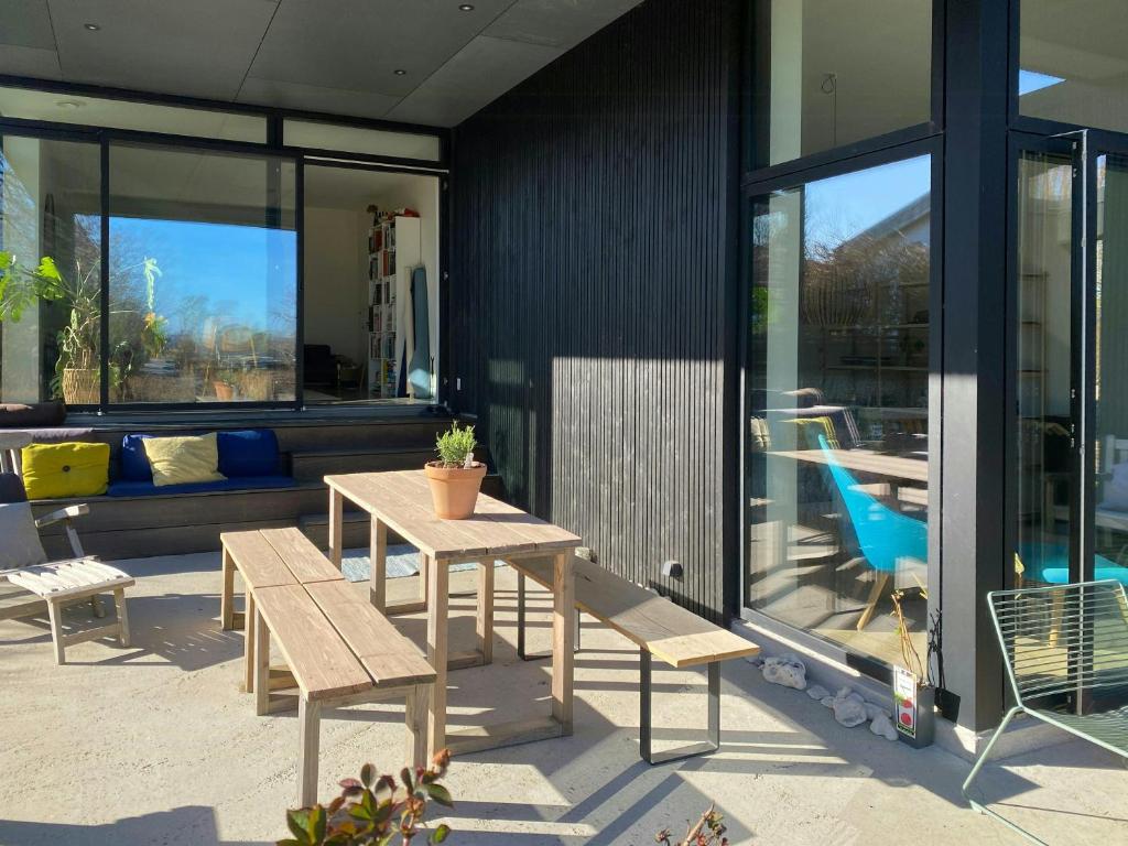 a patio with a table and benches and windows at Modern Beach House At Skæring Beach in Egå