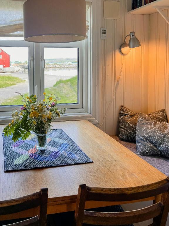 une table de salle à manger avec un vase de fleurs dessus dans l'établissement Northern Lights At Stetind Fishermans Cabin, à Storjord I Tysfjord