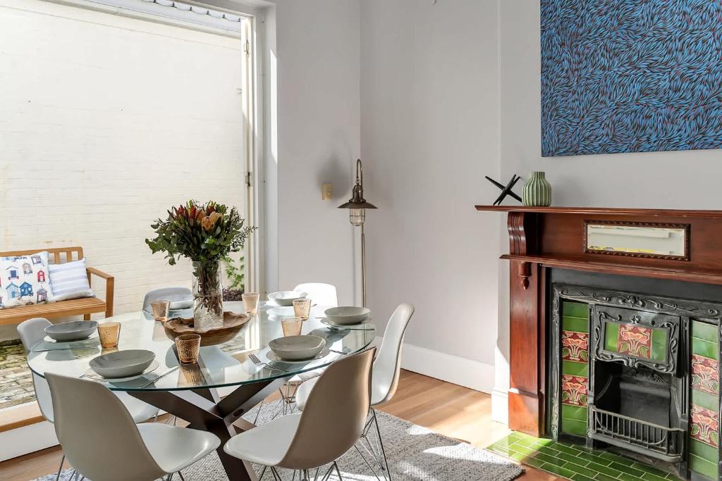 Un comedor con mesa y sillas y chimenea. en Marvelous Manly Home moments from the Beach - NEW, en Sídney