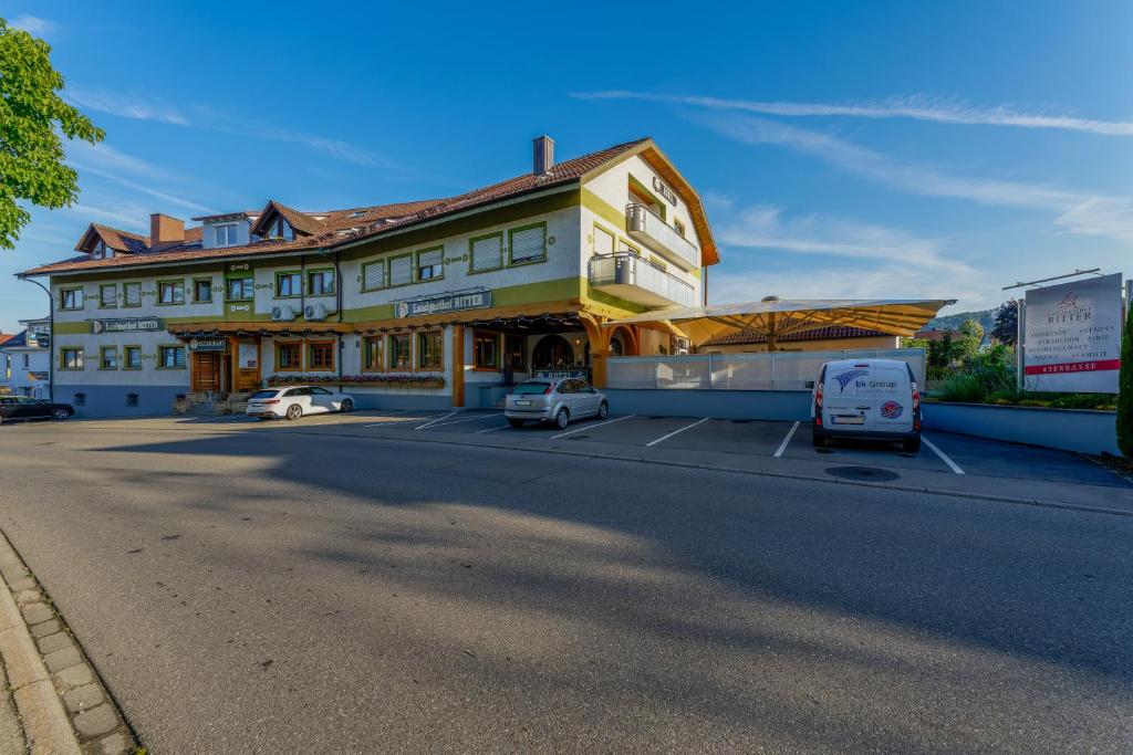un grande edificio giallo con auto parcheggiate in un parcheggio di Landgasthof Ritter a Orsingen-Nenzingen