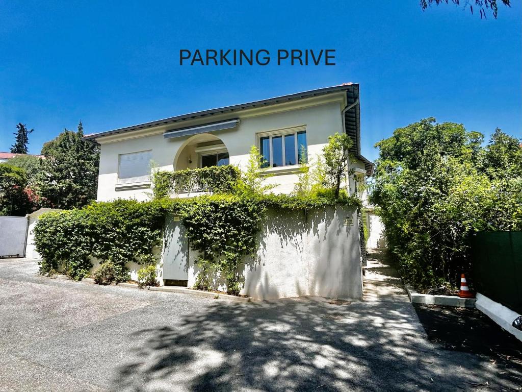 een wit huis met een hek en struiken bij Villa Etoile Cannes in Cannes
