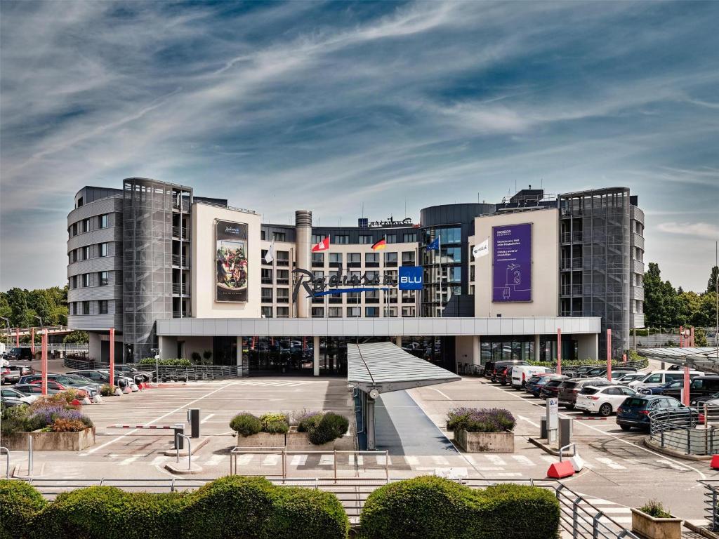a large building with cars parked in a parking lot at Radisson Blu Hotel, Hamburg Airport in Hamburg