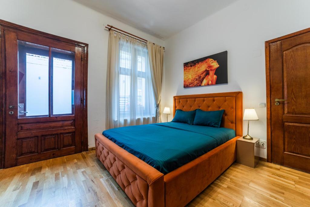 a bedroom with a bed with blue sheets and a window at Old City Lux 2 in Braşov