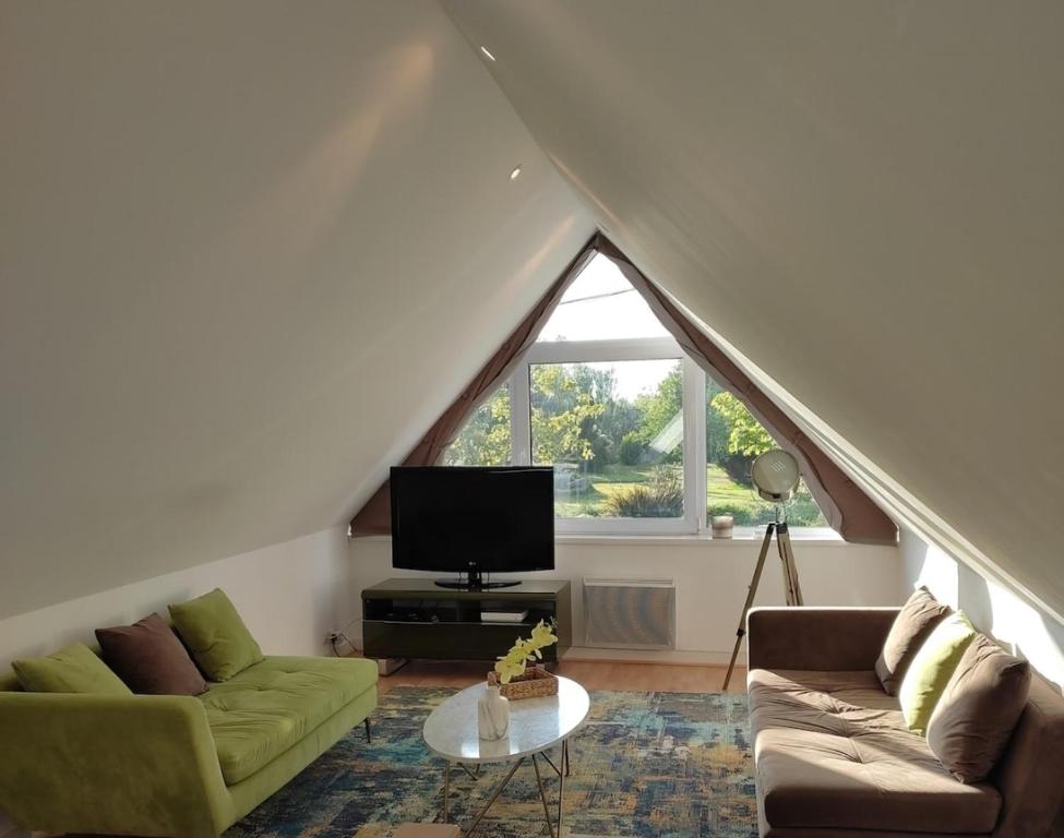 a living room with two green couches and a tv at Maison 4pers au calme vue Jardin in Roscoff