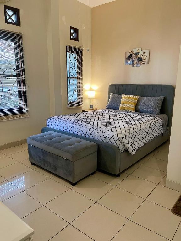 a bedroom with a bed and a ottoman and a window at Ndalem Suryo Guesthouse in Yogyakarta