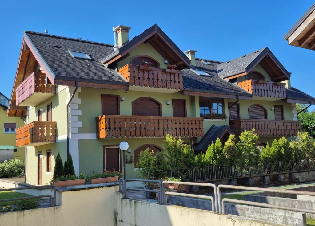 una casa con balcones y una valla en Montiva - The Green Lodge, en Asiago