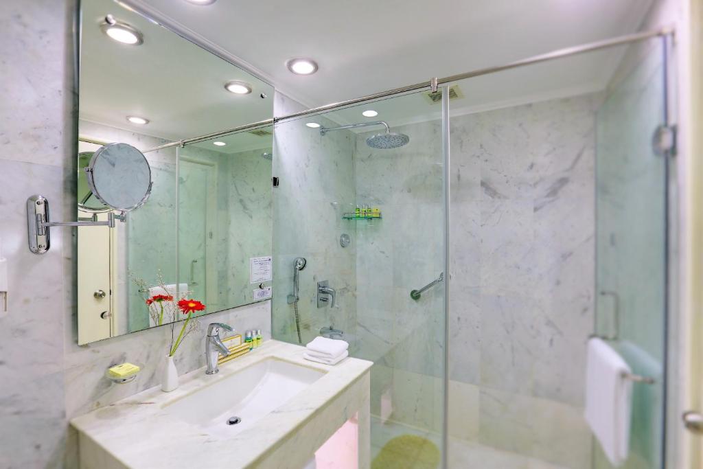 a bathroom with a shower and a sink and a mirror at Hotel Clarks Shiraz in Agra