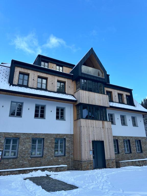 a building with snow on the ground in front of it at Apartmán Máj 104 in Pec pod Sněžkou