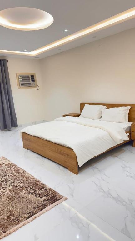 een slaapkamer met een groot bed in een kamer met marmeren vloeren bij شقق الربيع in Al Baha