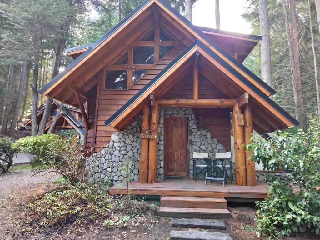 a log cabin with a porch and a wooden door at El Remanso - Arrayan Cabin, Bahía Manzano in Villa La Angostura