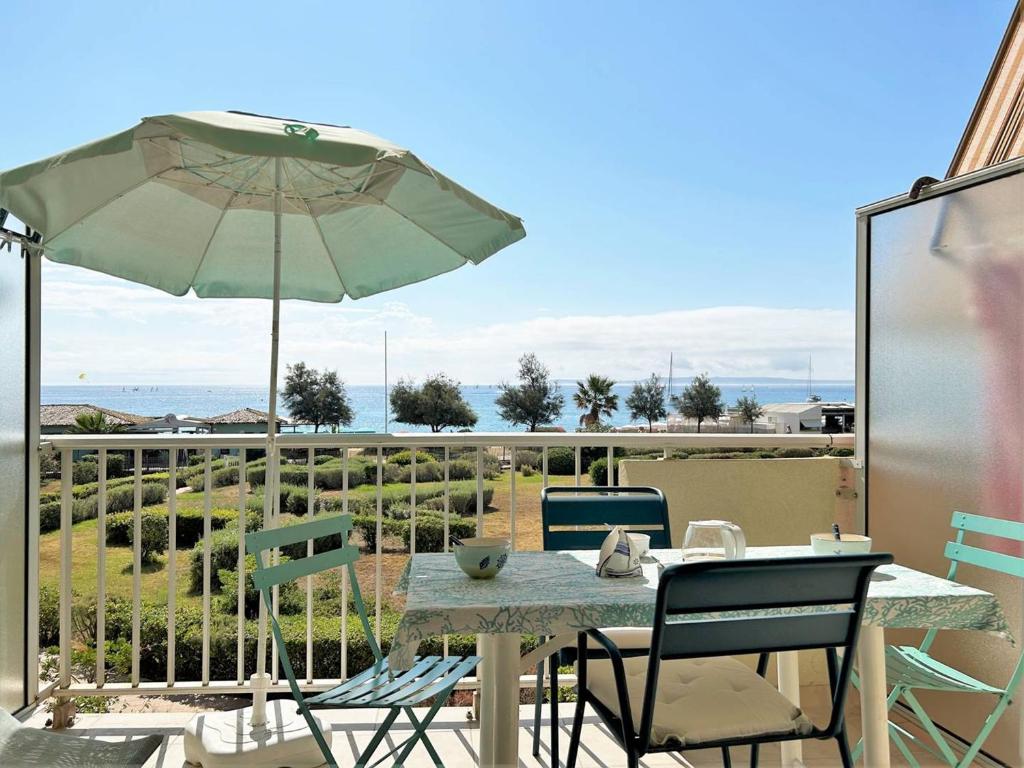 une table et des chaises avec un parasol sur un balcon dans l'établissement Appartement cosy 2 pièces avec parking - Le Lavandou - FR-1-251-381, au Lavandou