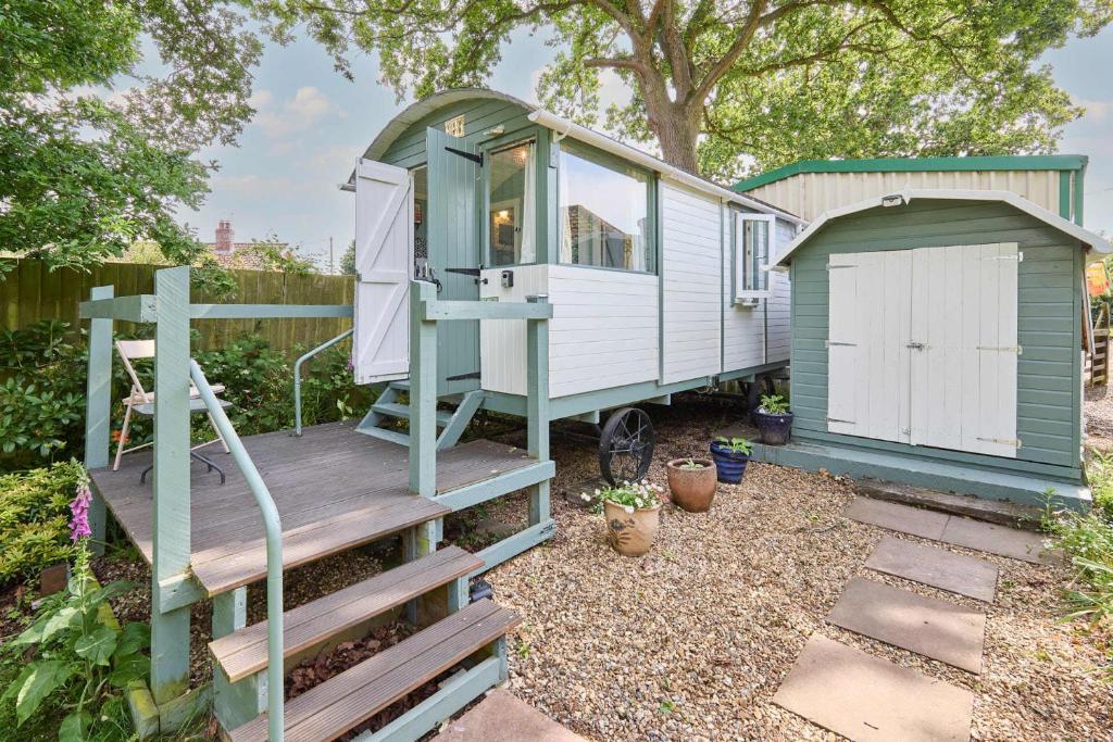 a green and white tiny house with a wooden deck at Host & Stay - Shepherd's Hut in Briston