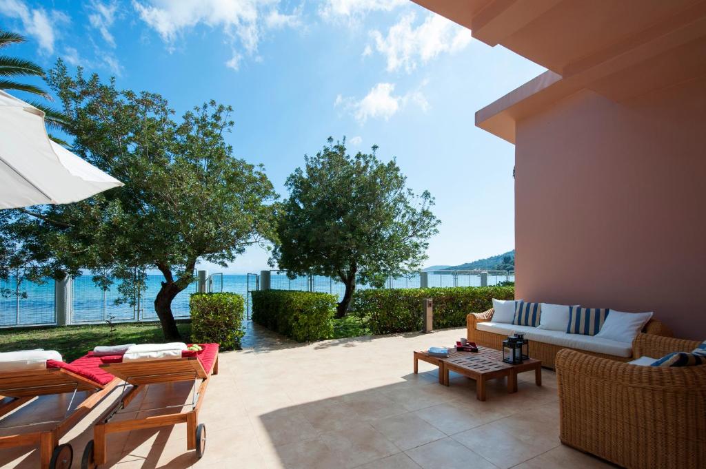 a patio with chairs and a couch and a table at Corfu Beachfront Villa in Mesongi