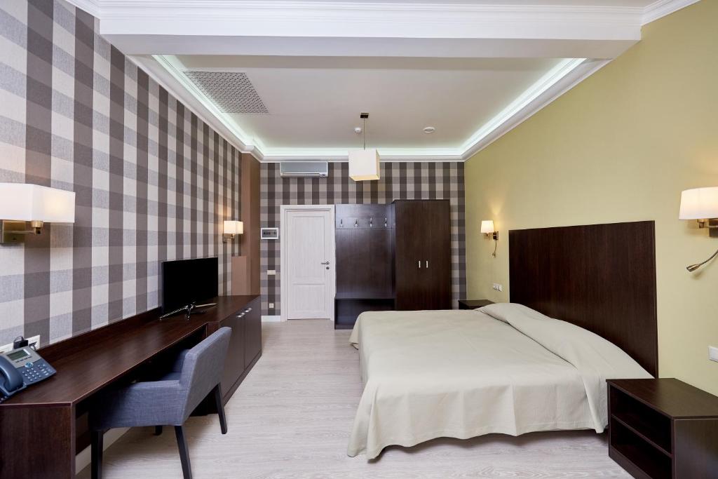 a bedroom with a bed and a desk and a television at Medical Hotel & SPA Tyumen in Tyumen
