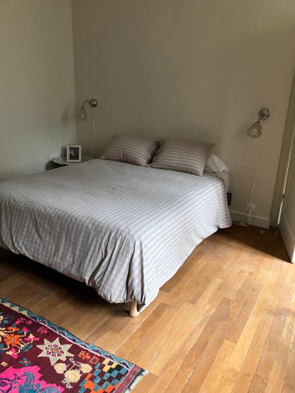 Cette chambre comprend un lit avec des draps blancs et du parquet. dans l'établissement Contes à Rebours - Chambres d'hôtes, à Morlaix