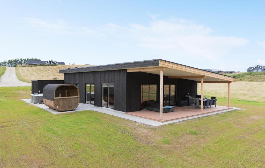 una casa negra con terraza en un campo en Lovely Home In Spøttrup With Sauna, en Lem