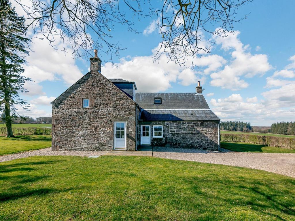 an old stone house on a grassy field at Meadowgreen Farmhouse in Forfar
