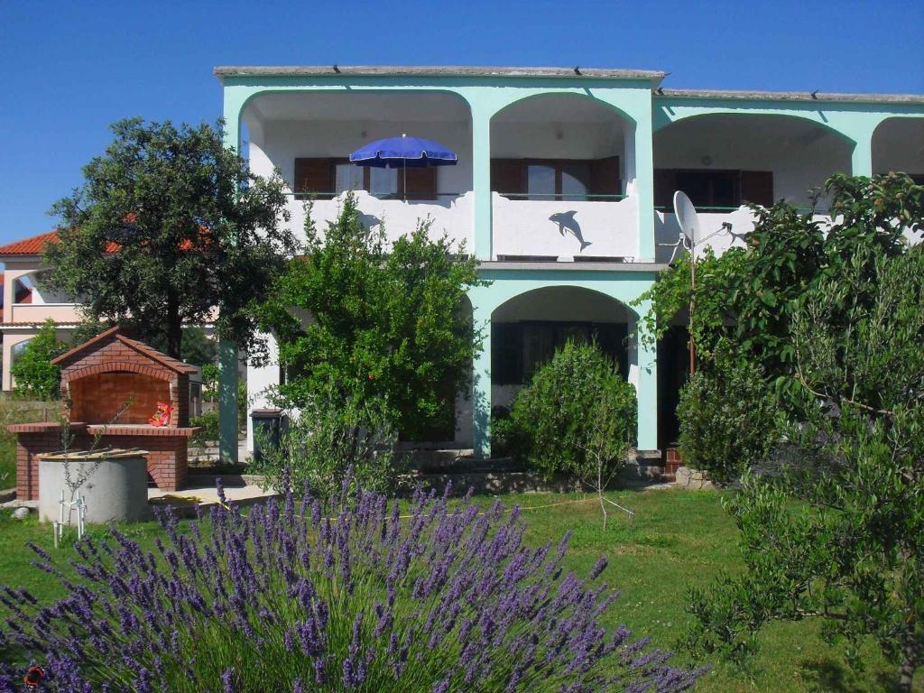 Una casa azul y blanca con una sombrilla en un patio. en Apartment Lopar 9, en Lopar