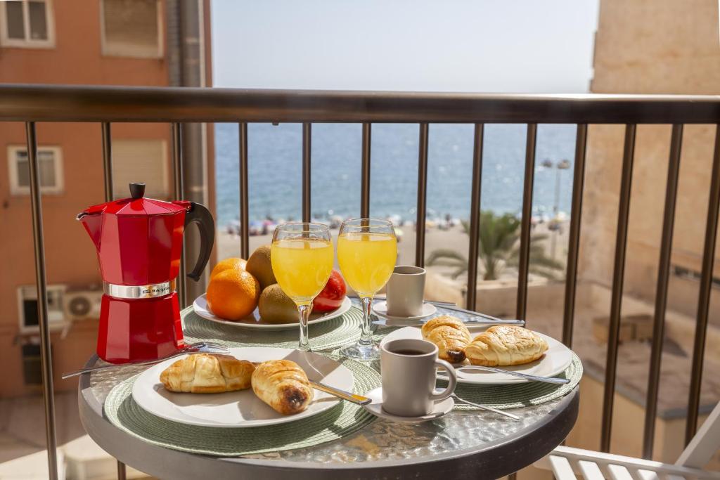 a table with two glasses of orange juice and pastries at AlmeriaSuite Las Caracolas Beach in Almería