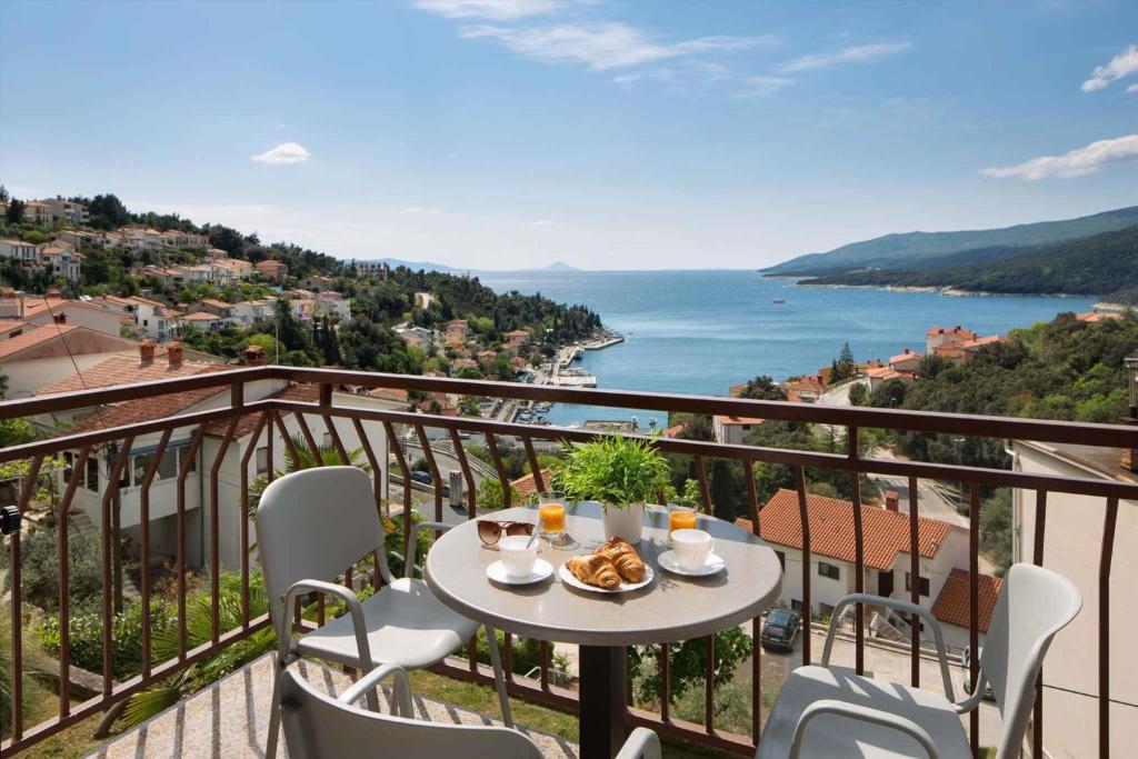 a table on a balcony with a view of the ocean at Apartment Rabac 11 in Rabac