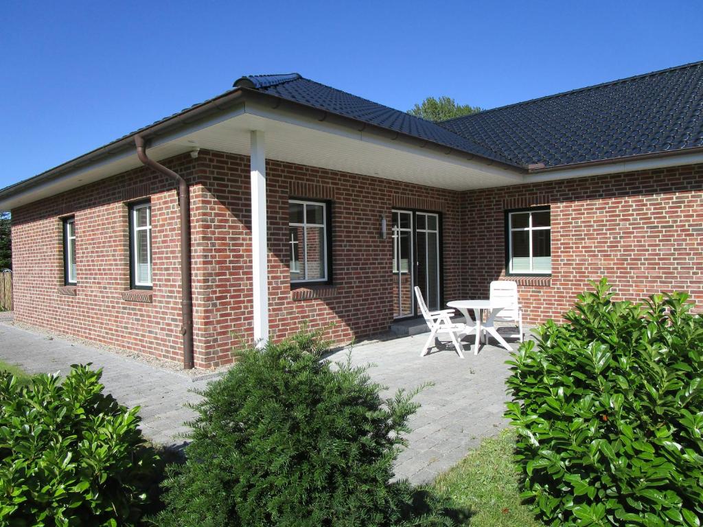 una casa de ladrillo con una mesa y sillas delante de ella en Wohnung im Bungalow, en Fehmarn