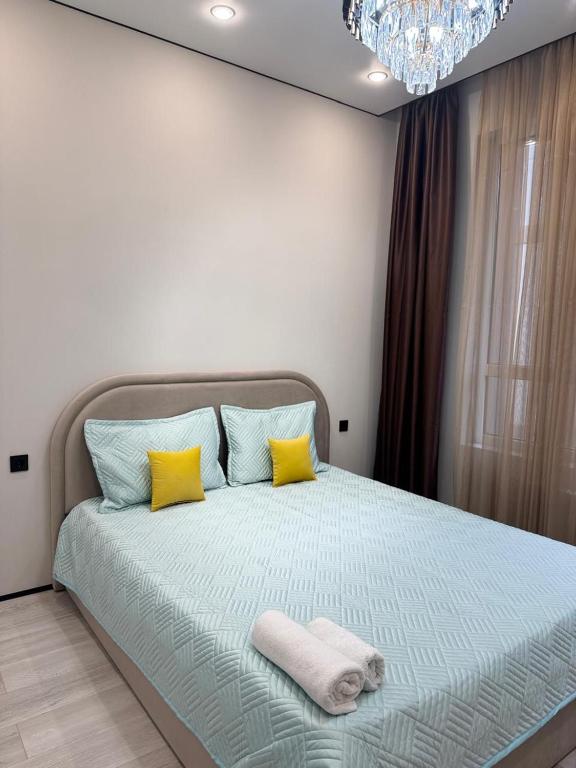 una camera da letto con un letto con cuscini gialli e blu di Роскошная двухкомнатная квартира a Almaty