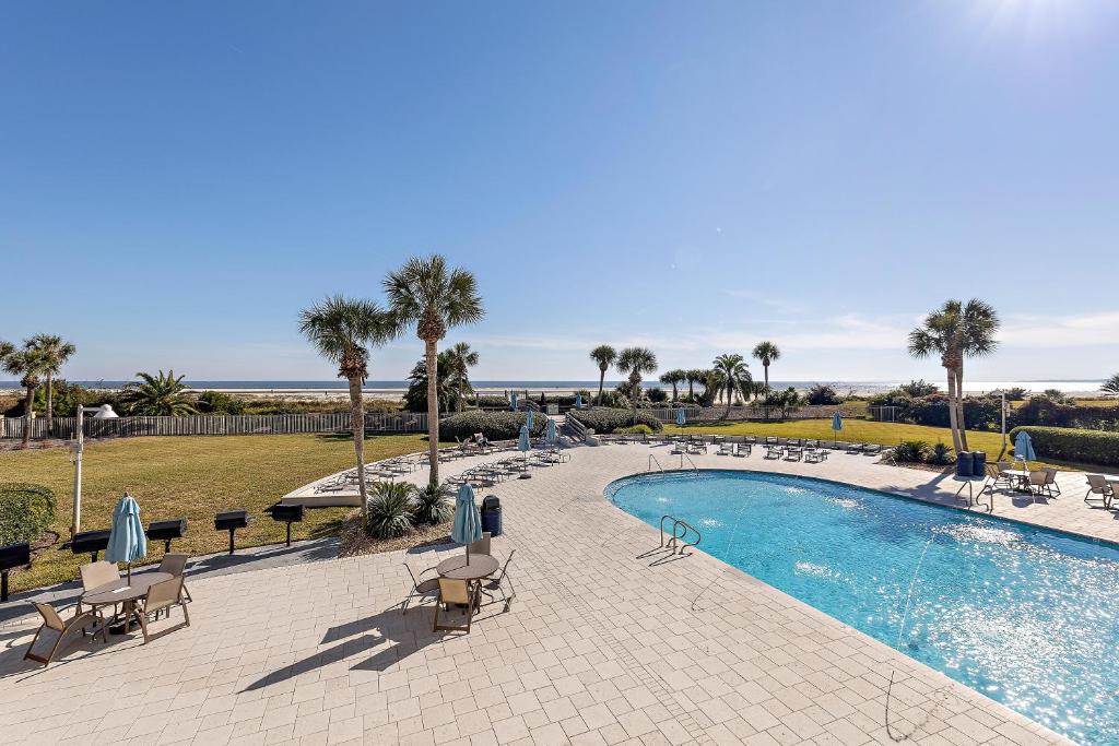 ein Schwimmbad mit Stühlen und Sonnenschirmen in der Unterkunft Beach Club #111 in Saint Simons Island